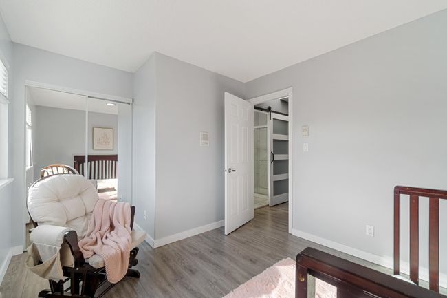 Bedroom featuring a barn door, multiple windows, wood finished floors, and baseboards | Image 17