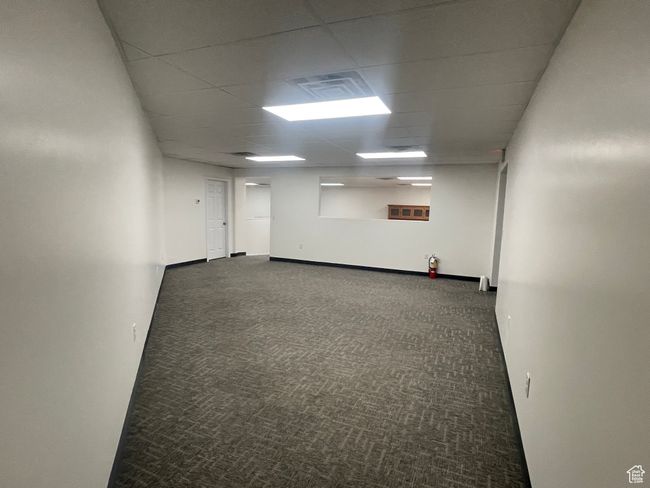 Empty room featuring carpet flooring, baseboards, a drop ceiling, and visible vents | Image 5