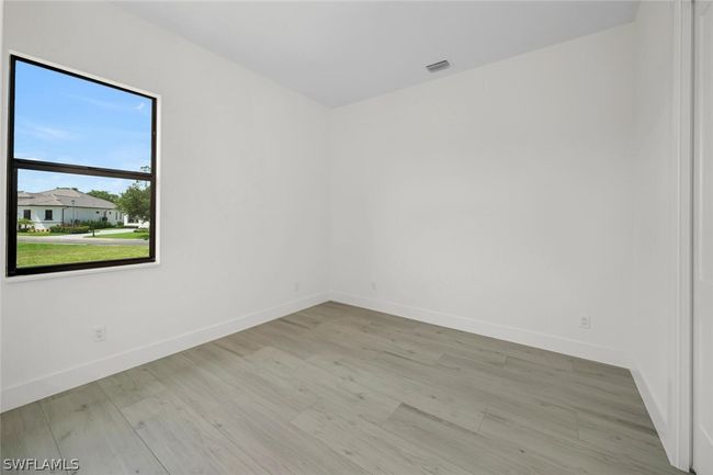 11'-6" x 11'-2" second bedroom with light wood-style plank flooring. Pool bath is just outside the bedroom door. | Image 14