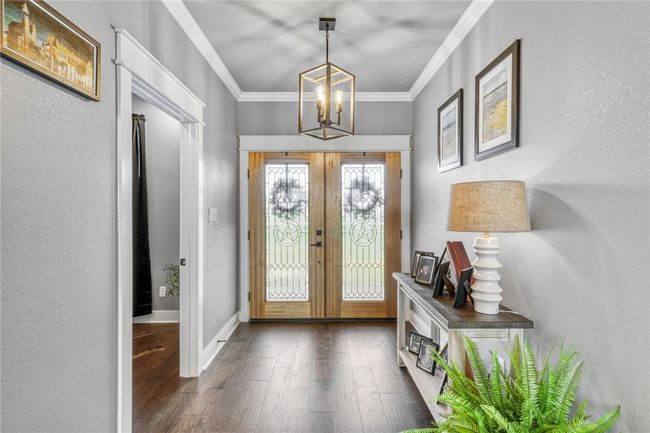 Foyer with french doors, ornamental molding, dark hardwood / wood-style flooring, and a notable chandelier | Image 9