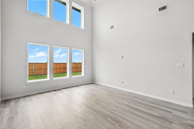 Empty room featuring a towering ceiling, wood finished floors, and healthy amount of natural light | Image 13