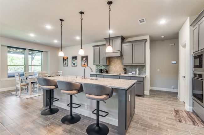 Kitchen featuring gray cabinets, light stone counters, a kitchen breakfast bar, wood tiled floors, and recessed lighting | Image 15
