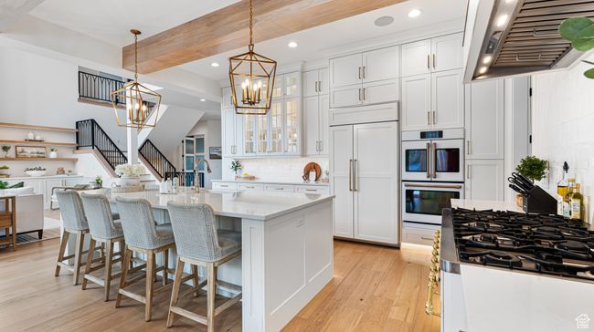 Kitchen featuring an inviting chandelier, exhaust hood, light wood-style floors, and paneled fridge | Image 24