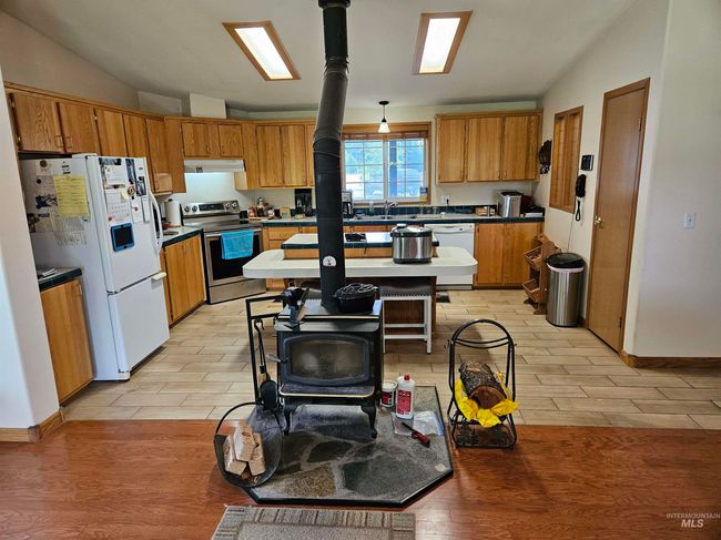 Kitchen with vaulted ceiling, light wood-type flooring, white appliances, and brown cabinetry | Image 5