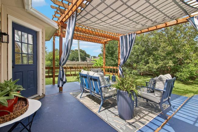 This inviting outdoor patio features a charming pergola with flowing curtains and lush greenery. It's perfect for relaxing and entertaining in a serene backyard setting. | Image 26
