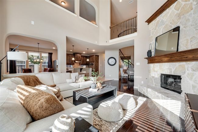Living room with stairway, wood finished floors, a towering ceiling, arched walkways, and a stone fireplace | Image 9