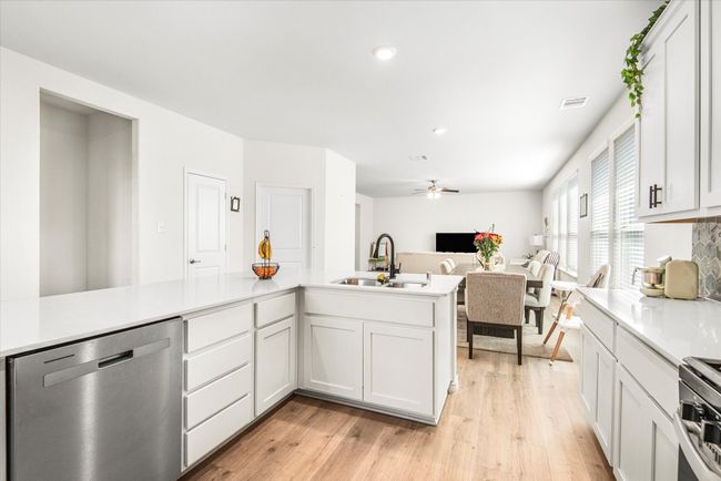Kitchen featuring light wood-type flooring, appliances with stainless steel finishes, light countertops, and a sink | Image 12
