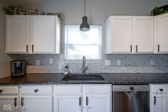 kitchen featuring stainless steel dishwasher, a sink, white cabinets, and backsplash | Image 14