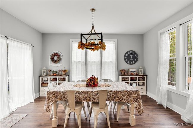 Dining area featuring dark wood-type flooring, baseboards, and a chandelier | Image 16