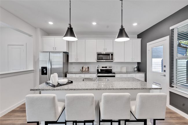 Kitchen featuring appliances with stainless steel finishes, white cabinets, a kitchen island with sink, and a sink | Image 12