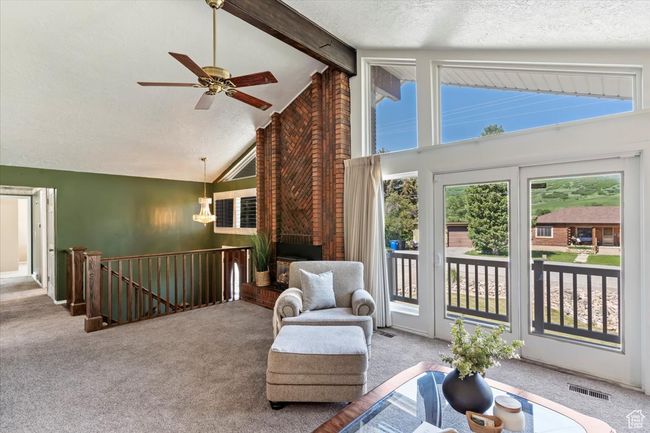 Sitting room with carpet, an upstairs landing, a ceiling fan, beam ceiling, and high vaulted ceiling | Image 10