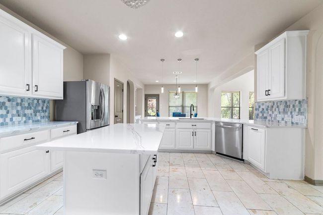 Kitchen featuring stainless steel appliances, recessed lighting, a peninsula, tasteful backsplash, and white cabinetry | Image 18
