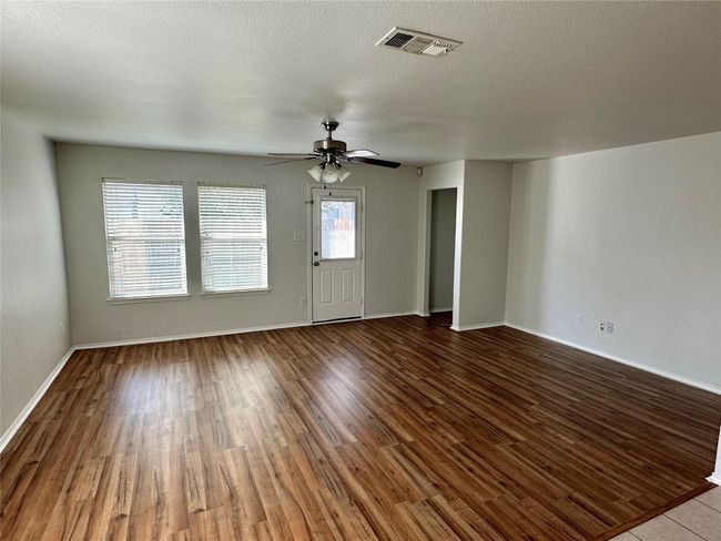 Spare room featuring baseboards, a textured ceiling, ceiling fan, visible vents, and wood finished floors | Image 5
