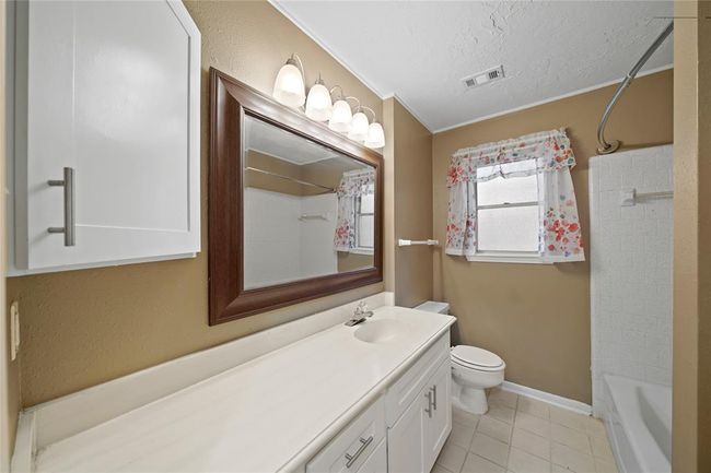 Secondary bathroom located between the two bedroom from the hallway, features a large mirror above a one sink, white vanity. It has a shower-tub combo and plenty of storage space. | Image 22