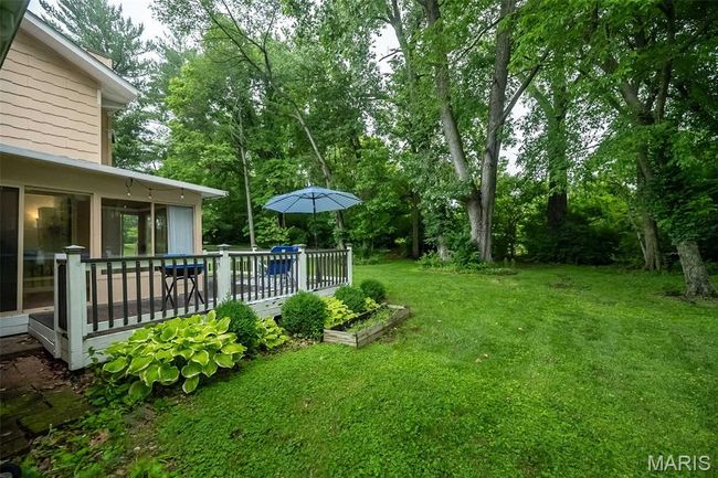 View of grassy yard featuring a deck, a sunroom, and view of scattered trees | Image 30