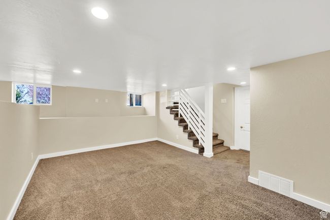 Basement with carpet floors, visible vents, baseboards, and stairway | Image 18