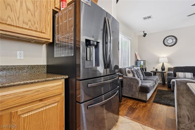 Kitchen featuring stainless steel fridge, wood finished floors, dark stone counters, and open floor plan | Image 27