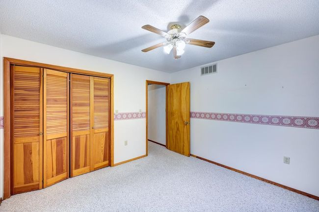 Unfurnished bedroom with light colored carpet, a closet, baseboards, a textured ceiling, and a ceiling fan | Image 11