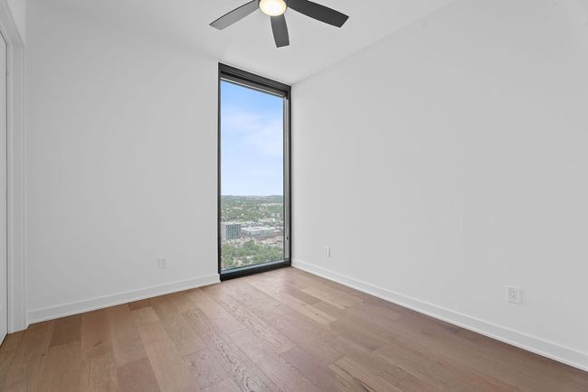 Unfurnished room with a wall of windows, wood finished floors, and a ceiling fan | Image 21