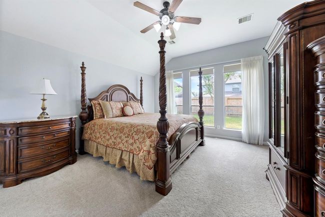 The spacious primary suite offers a serene view of the backyard through a wall of tall windows, creating a private and peaceful retreat. | Image 14