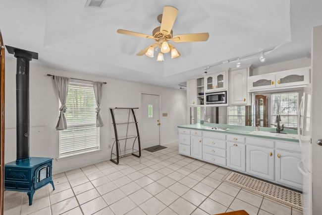 Kitchen with white cabinets, a wood stove, a sink, and stainless steel microwave | Image 34