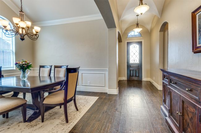 Dining room featuring crown molding, a notable chandelier, arched walkways, and dark wood-style flooring | Image 6