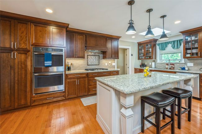 Kitchen featuring stainless steel appliances, decorative backsplash, light wood finished floors, glass insert cabinets, and recessed lighting | Image 6