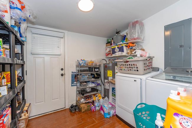 Clothes washing area featuring laundry area, electric panel, independent washer and dryer, wood finished floors, and electric water heater | Image 12