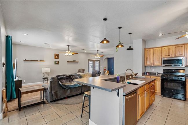 Kitchen featuring sink, a breakfast bar area, hanging light fixtures, stainless steel appliances, and an island with sink | Image 15
