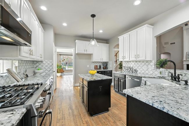 Kitchen with appliances with stainless steel finishes, white cabinetry, light wood-style flooring, light stone counters, and recessed lighting | Image 9