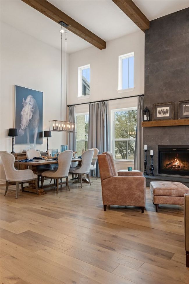 Living area with beam ceiling, a towering ceiling, a large fireplace, a chandelier, and hardwood / wood-style flooring | Image 22