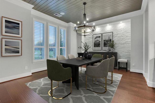 This dining room features is brightened by large windows with shutters, a light accent mosaic stone wall, and a decorative ceiling. | Image 12