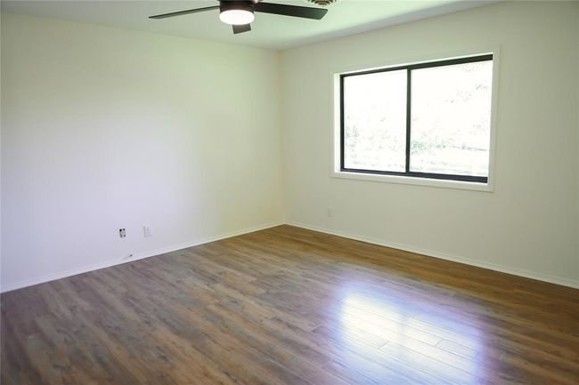 Primary bedroom with new hardwood floors looking out through the new window to the backyard | Image 15