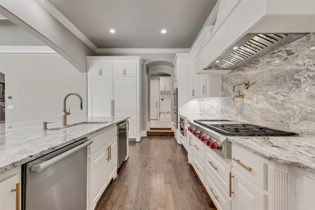 Kitchen featuring stainless steel appliances, arched walkways, a sink, crown molding, and under cabinet range hood | Image 14