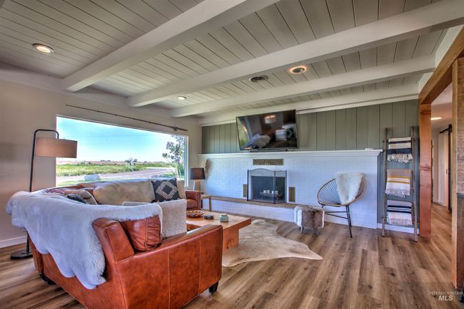 Living room featuring a fireplace, wood finished floors, and a wooden ceiling with exposed beams | Image 5