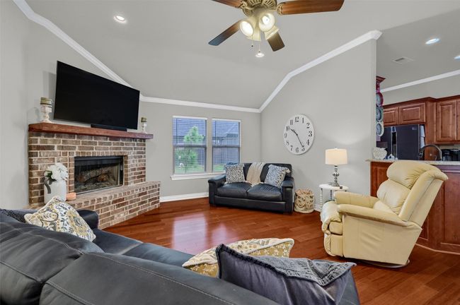 Living area featuring vaulted ceiling, crown molding, wood finished floors, and a ceiling fan | Image 9