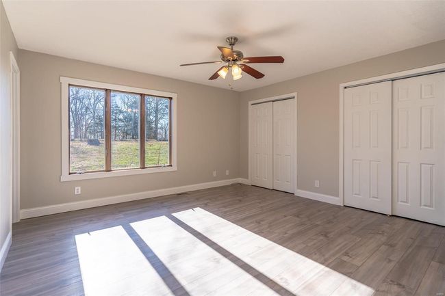 Unfurnished bedroom featuring wood-style floors, ceiling fan, and multiple closets | Image 20