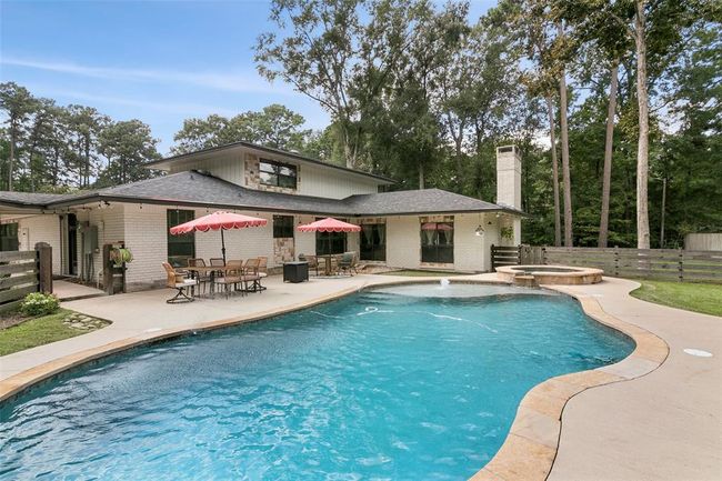 This spacious home features a beautiful backyard with a large, curved swimming pool and attached spa, surrounded by a patio for outdoor dining and relaxation. The property is bordered by tall trees, providing a serene and private setting. | Image 45