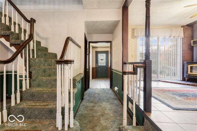staircase featuring a wood stove, tile patterned floors, and carpet flooring | Image 10