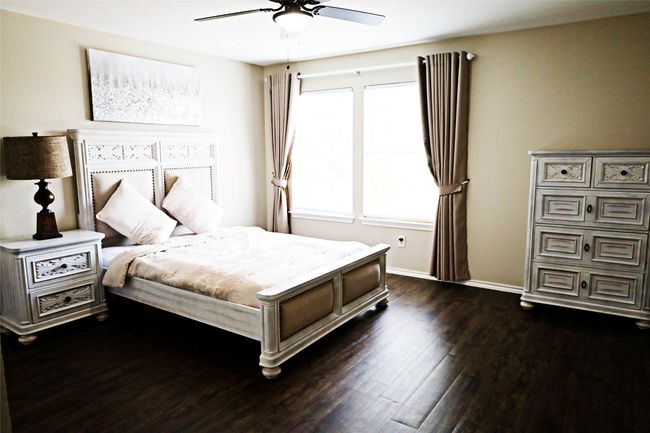 Bedroom with dark wood-style floors, baseboards, and a ceiling fan | Image 8