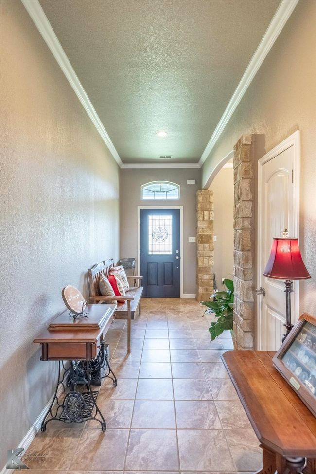 Foyer entrance with arched walkways, crown molding, a textured ceiling, and a textured wall | Image 4
