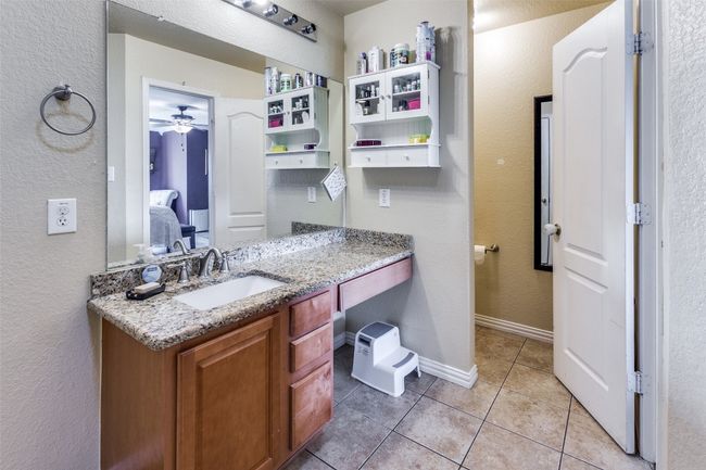 Ensuite bathroom with tile patterned flooring, a textured wall, vanity, ceiling fan, and baseboards | Image 35