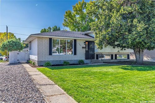 White brick exterior with black shutters, mature trees, and a concrete pathway | Card Image
