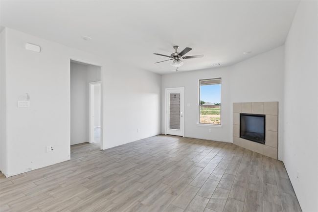 Unfurnished living room featuring light hardwood / wood-style flooring, a tile fireplace, and ceiling fan | Image 12