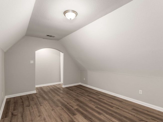 Additional living space with visible vents, baseboards, vaulted ceiling, arched walkways, and dark wood-style floors | Image 38