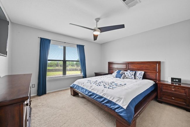 Bedroom with light colored carpet, baseboards, and ceiling fan | Image 28