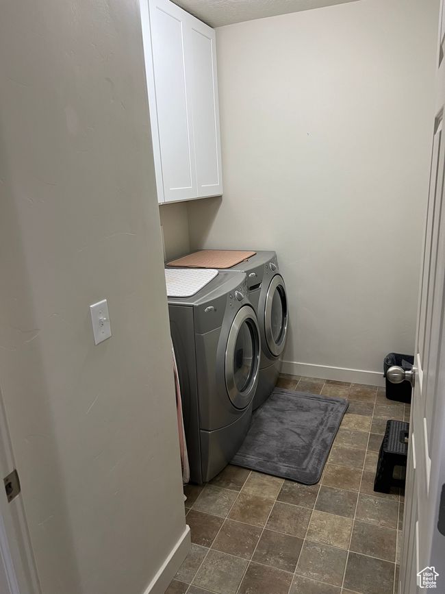 Washroom with baseboards, stone finish flooring, washer and dryer, and cabinet space | Image 17