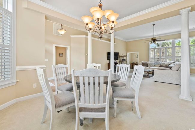 Dining space featuring visible vents, ornamental molding, ceiling fan with notable chandelier, and light carpet | Image 5