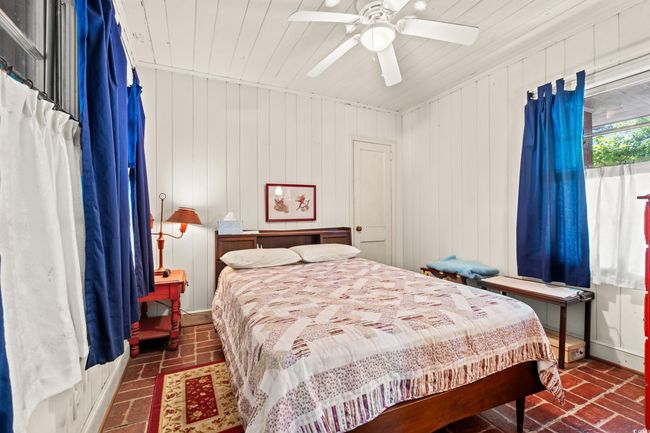 Bedroom featuring brick floors, wood ceiling, and ceiling fan | Image 13