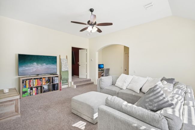 Carpeted living room featuring visible vents, ceiling fan, arched walkways, and lofted ceiling | Image 27